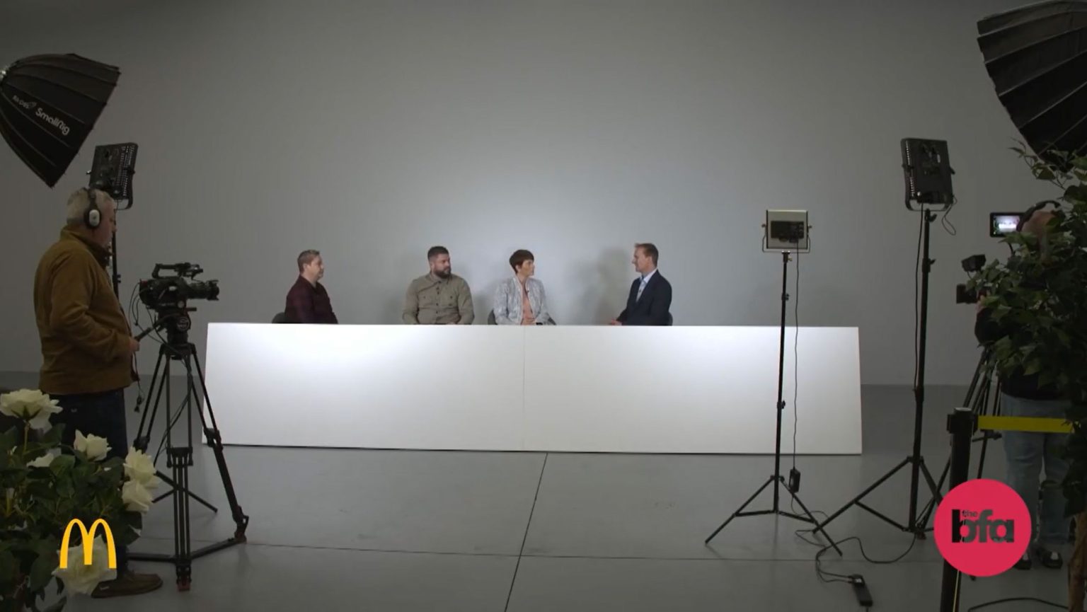 Camera operator recording a host and a panel of 3 people during a live stream.